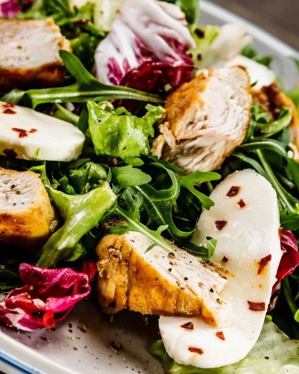 A plate of grilled chicken, pear and leaves